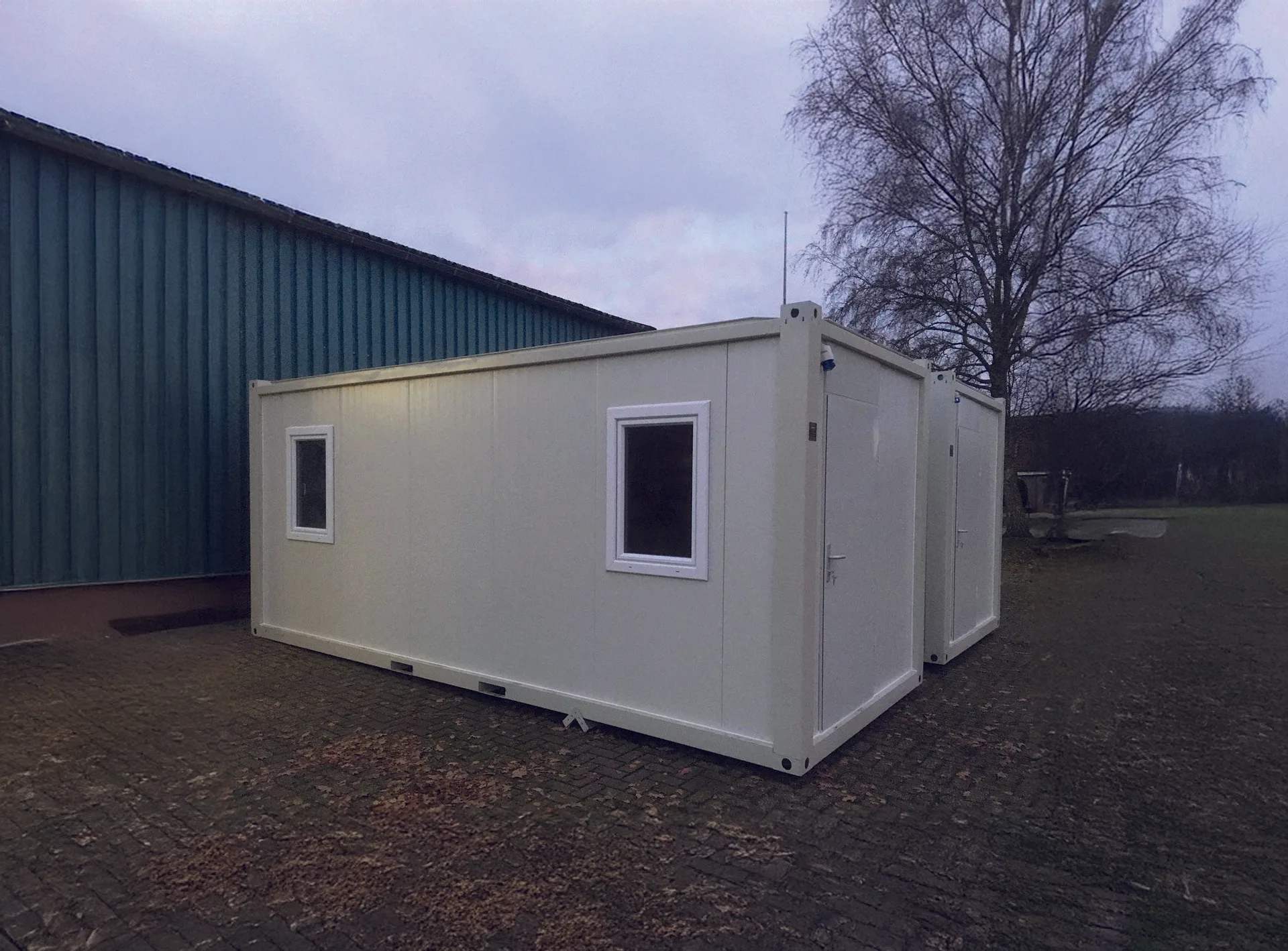 P2240 S flatpack container — installation context with paired units on a hardstand yard under overcast sky.