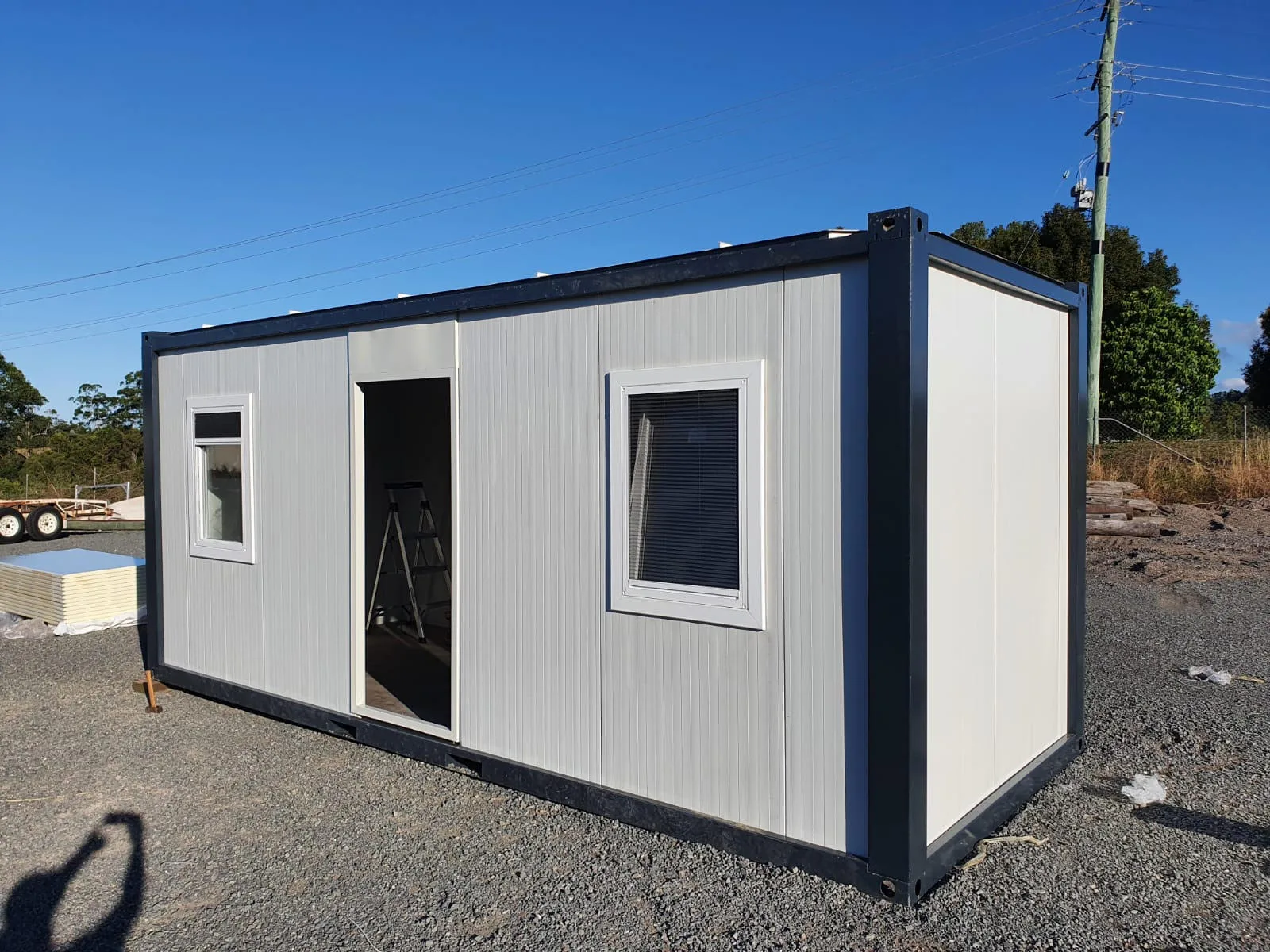 P2460 L flatpack container — three-quarter exterior view in active construction site setting.