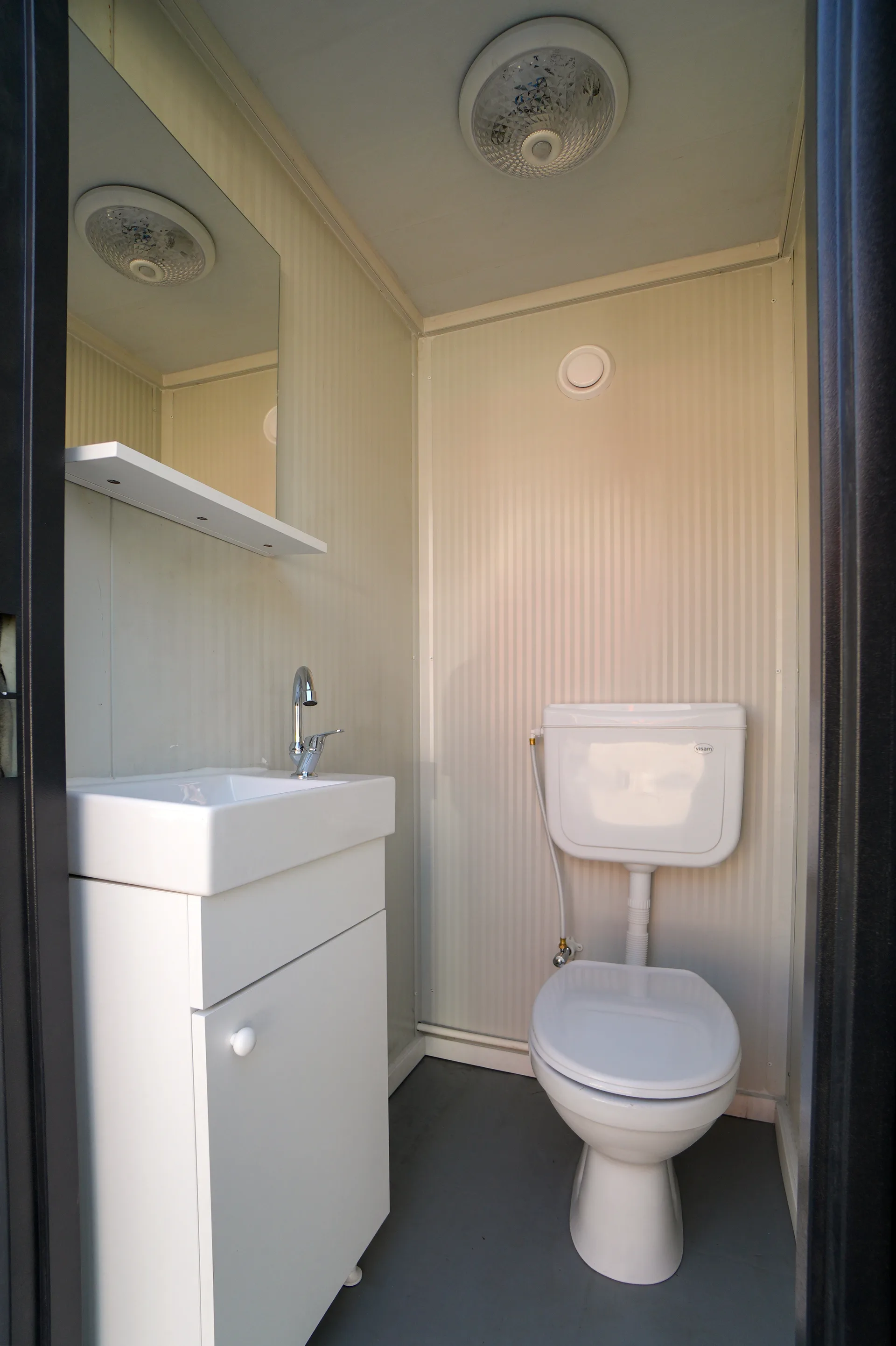 T135D double WC — adjacent cubicle with ventilation grille.